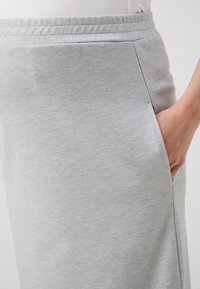 Lys grå jersey skjørt med en avslappet passform, elastisk midje og sidelommer. Materialet har en myk, glatt tekstur.