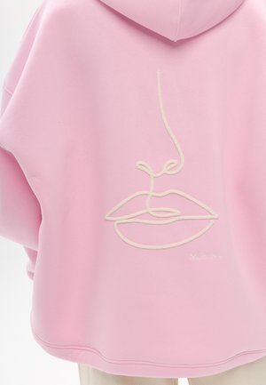 Rosa Kapuzenpullover mit einem gestickten Linienbild von Lippen und Nase in Creme, mit lockerem Schnitt und weicher Textur.