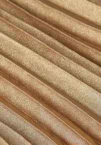 Tissu doré scintillant avec une texture ondulée et plissée. Des teintes claires et foncées alternées créent de la profondeur et de l'intérêt visuel. Surface douce et réfléchissante.