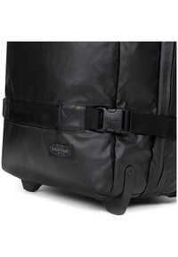 Borsa da viaggio nera con ruote, realizzata in un tessuto testurizzato e resistente, dotata di una robusta fibbia, angoli rinforzati e il logo Eastpak.