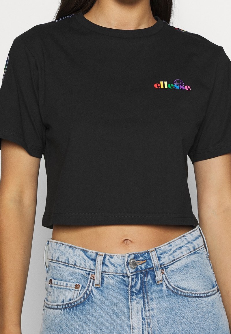 Camiseta negra recortada con mangas cortas, que presenta un logo "ellesse" multicolor en el lado izquierdo del pecho y acentos a rayas en contraste en los hombros.