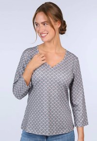 Grau gemusterte Bluse mit V-Ausschnitt und Dreiviertelärmeln, die ein sich wiederholendes Blattdesign in Hellrosa und Weiß aufweist. Weicher Stoff.