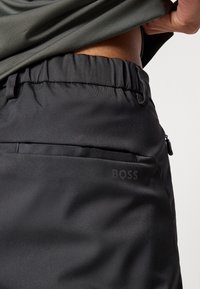 Μαύρα σορτς με ελαστική μέση, που διαθέτουν πλαϊνή τσέπη με φερμουάρ και διακριτικό λογότυπο "BOSS" στο ύφασμα. Ομαλή υφή.