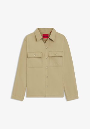 Beige button-up shirt with long sleeves, two chest pockets, and HUGO branding. Features a classic collar and smooth texture.