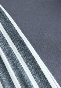 Szövet sötétszürke anyagból és egy farmerkék csíkkal, amely kék és fehér csíkokat tartalmaz. A felület sima, puha tapintású.