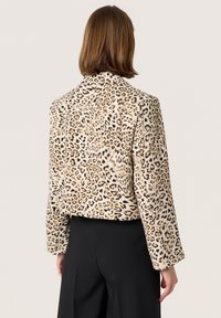 Leopardmønstret faux fur-jakke med en tætsiddende pasform, skræddersyet krave og lange ærmer. Det teksturerede stof har mørke og lyse pletter.