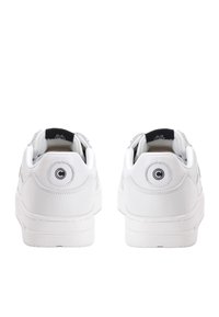 Scarpe da ginnastica bianche con una tomaia in pelle liscia, dettagli in rete e una linguetta nera sul tallone. Dettaglio logo circolare sul tallone. Design low-top.