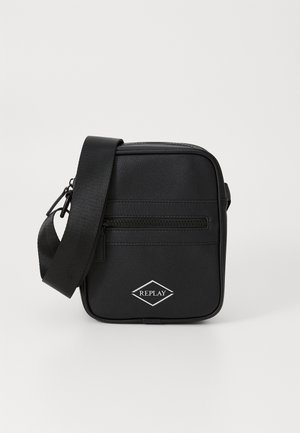 Svart crossbody-veske laget av teksturert lær med polstret stropp, med en frontlomme med glidelås og en diamantlogo-detalj.