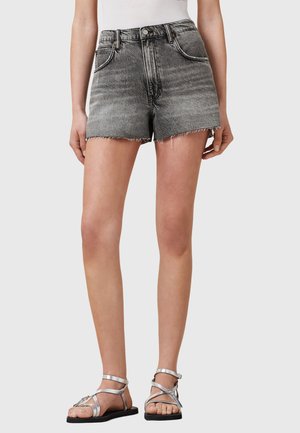 Shorts in denim nero con orlo sfilacciato, vestibilità alta e design a cinque tasche. Abbinati a sandali argentati con cinturini.