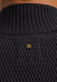 Maglione lavorato a maglia grigio scuro con colletto a coste e corpo testurizzato. Presenta un piccolo etichetta nera e gialla con la scritta "PME LEGEND" sul retro.