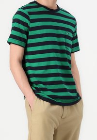 Viher- ja laivastonsinisiä raitapaitoja, joissa on pyöreä pääntie ja rintatasku. Valmistettu pehmeästä puuvillakankaasta, jossa on lyhyet hihat ja rento leikkaus.