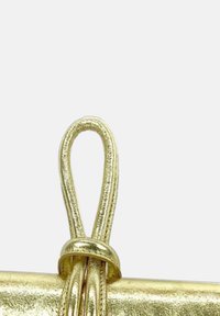 Fermoir en métal doré avec un design en boucle, présentant une texture lisse et brillante ainsi qu'une forme cylindrique, idéal pour maintenir des accessoires.