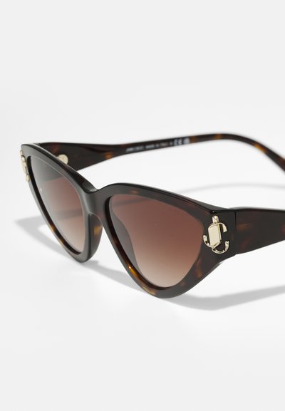 Lunettes de soleil en écaille de tortue avec des verres dégradés bruns et des accents en métal doré sur la monture. Fini plastique lisse.