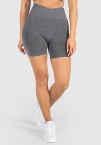 Shorts gris taille haute en tissu extensible avec une texture lisse. Dispose d'une large ceinture et d'un design ajusté, associés à des chaussures blanches.