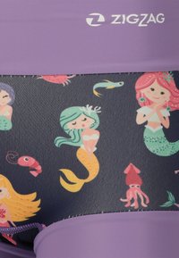 Maillot de bain avec un fond sombre et des motifs colorés de sirènes et de créatures marines. Accentué par une taille élastique violette et un logo en zigzag.