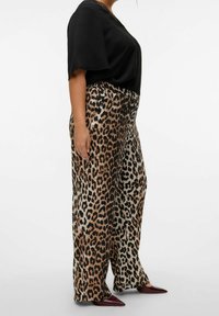 Løveprint brede ben bukser med en glat tekstur og høj talje, parret med en løs sort top med korte ærmer og rund hals.