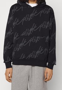 Schwarzer Hoodie aus weichem Stoff, mit einem grauen, wiederholten Logo-Druck, Kängurutasche und gerippten Bündchen und Saum.