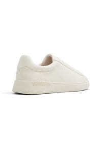 Sneaker bianca in pelle con profilo basso, punta tondeggiante, design minimalista, dettaglio testurizzato sul tallone e suola in gomma.