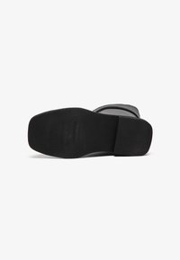 Sort gummisål med tekstureret overflade; designet med en let kurve. Overdelen har et glat gråt tekstilmateriale med minimalistisk stil.