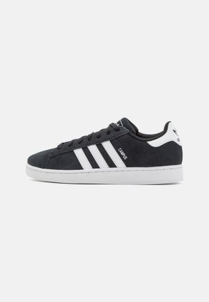 Lavtop sort ruskind sneaker med hvid sål, tre hvide striber på siden og tekst "Campus" nær snørebåndene.