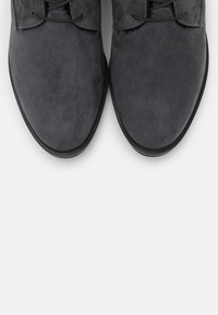 Chaussures en daim gris avec une texture lisse et un embout arrondi, dotées de lacets et d'une semelle en caoutchouc noire. Design simple et élégant.