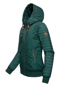 Veste à capuche bleu teal avec des pois blancs et des motifs en zigzag, fermeture éclair à l'avant, poignets élastiques et accents en cuir marron sur la poitrine et la fermeture éclair.