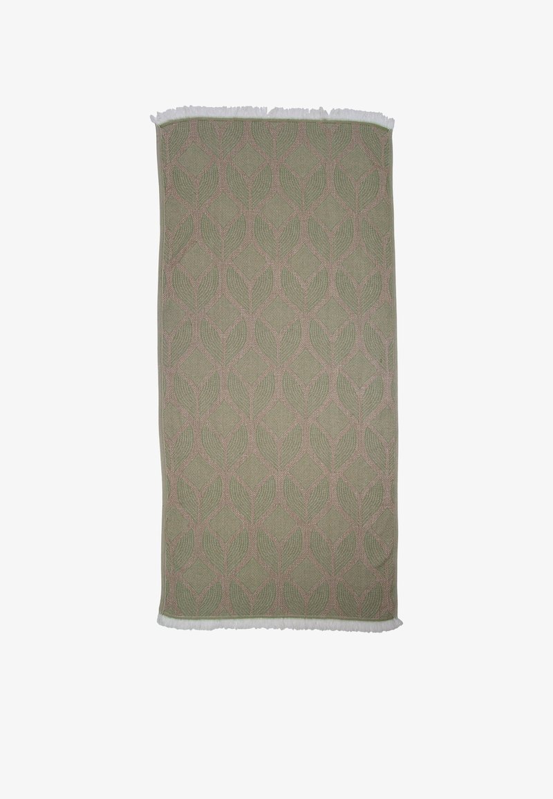 Rechthoekig groen vloerkleed met een geometrisch bladerenpatroon in beige, voorzien van witte franjes aan de kortere randen.