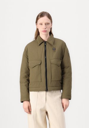 Olijfgroene cropped jas met een ritssluiting, twee voorzakken en een staande kraag. Gelaagd weefsel met subtiele stikdetails.