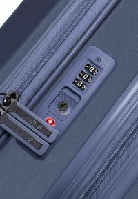 Blaue Hartschalenkoffer mit strukturierten Oberflächen, ausgestattet mit einem Kombinationsschloss, TSA-Schlüsselloch und Doppelreißverschlüssen mit eingraviertem Markenlogo.