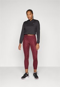 Black cropped hoodie with a hood; burgundy leggings featuring an abstract pattern; black athletic shoes with pink accents.