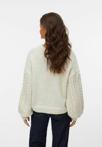 Cremefarbenes, übergroßes Strickpullover mit Kabelstrickärmeln und strukturiertem Körper. Hat einen geribbelten Saum und breite Manschetten. Lässiges Design.