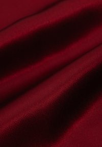 Bordo materiał o gładkiej fakturze, z subtelnym połyskiem i pofałdowanej powierzchni, pokazujący różne refleksy światła.