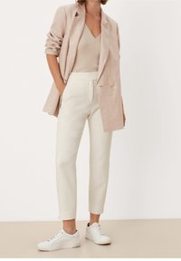 Jasnoróżowa lniana marynarka, beżowy prążkowany top na ramiączkach, kremowe eleganckie spodnie i białe trampki. Cecha charakterystyczna to luźny krój i subtelne detale.