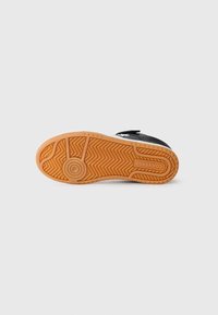 Svarta sneakers med gummisula, med ett fiskbensmönster. Yttersulan är gummifärgad med ett cirkulärt logomärke.