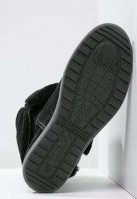 Stivale in suede nero con suola in gomma testurizzata. Presenta punta e collo rinforzati, con un logo in rilievo sulla suola.