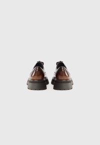 Brown leather shoes with a thick black rubber sole, featuring a brogue design and lace-up front. Smooth texture with glossy accents.