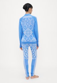 Blue patterned thermal set featuring intricate white designs, long sleeves on the top, and fitted leggings with a smooth texture.