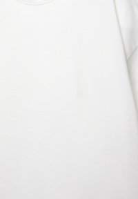 Hvid bomulds T-shirt med korte ærmer og rund halsudskæring, der har en glat tekstur og minimale syninger.