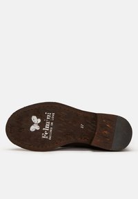 Semelle de chaussure en bois brun avec surface texturée, inscription de la marque "Falling in Love", pointure 37, talon arrondi et légère usure.