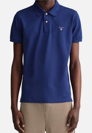 Navy blauwe polo-shirt van katoen, met een klassieke kraag, een knoopsluiting met twee knopen en een klein geborduurd logo op de borst.
