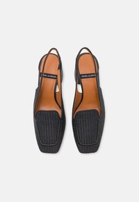 Sandales à talons noires à bout découvert avec un upper en tissage texturé et une semelle intérieure lisse couleur tan. Design à bout carré avec peu de détails matériels.
