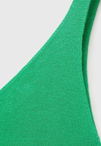 Țesătură tricotată verde, formă triunghiulară, textură netedă, cu un finisaj ribbat și curele subțiri. Imagine de aproape evidențiind detaliile materialului.