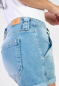 Lichtblauwe denim shorts met een opgerolde zoom, voorzien van een leren label op de tailleband en achterzakken met subtiele stikdetails.