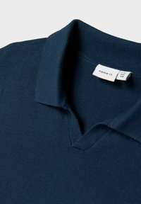 Tamsiai mėlynas megztas polo marškinėliai su raukšlėta apykakle ir prekės ženklu "name it" siuvinėtų vidinėje apykaklėje.