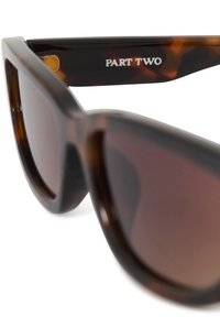 Lunettes de soleil écaille marron avec verres rectangulaires foncés et "PART TWO" imprimé à l'intérieur de la branche.