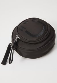 Czarna okrągła torba wykonana z nylonu, charakteryzująca się gładką teksturą, zapięciem na zamek oraz wytłoczonym wzorem uśmiechniętej buźki z przodu.