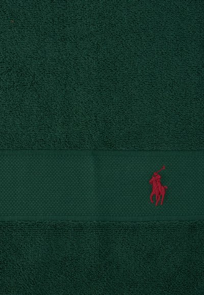 Σκούρο πράσινο ύφασμα πετσέτας με υφασμένη ταινία και μικρό κόκκινο κεντητό λογότυπο παίκτη πόλο πάνω σε άλογο.
