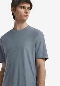 Grå kortärmad t-shirt i mjukt, strukturerat tyg med rund halsringning. Har en avslappnad passform och en subtil horisontell mönstring.