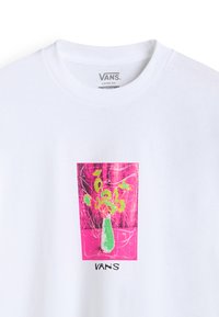 Vit, oversized t-shirt med en färgglad grafik av en grön vas med blommor på en rosa bakgrund; varumärket "VANS" tryckt nedanför.