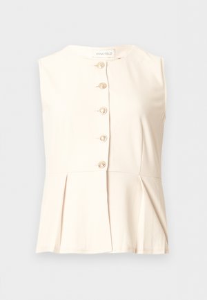 Αμάνικη κρεμ μπλούζα με στρογγυλή λαιμόκοψη, πέντε διακοσμητικά χρυσά κουμπιά στο μπροστινό μέρος και πιετέ λεπτομέρεια στη μέση.